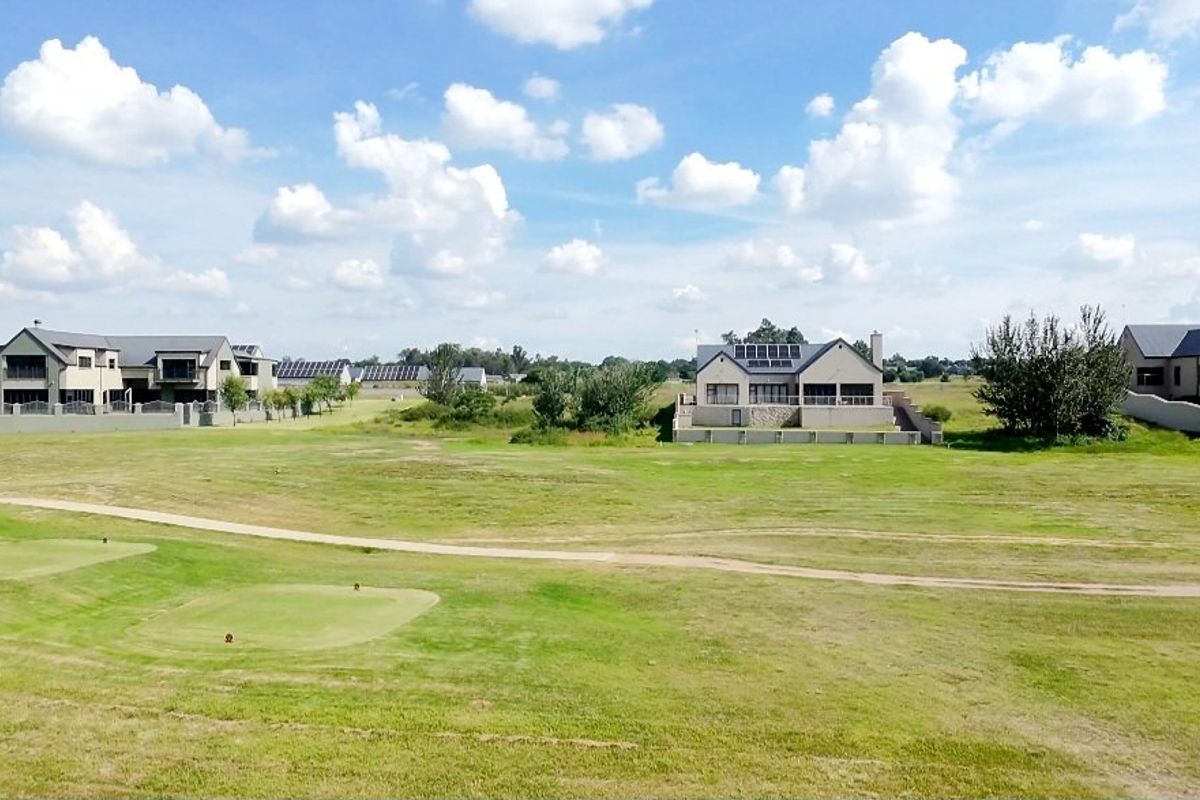An elevated view of a residential estate featuring open green spaces, manicured lawns, and surrounding modern residential properties.