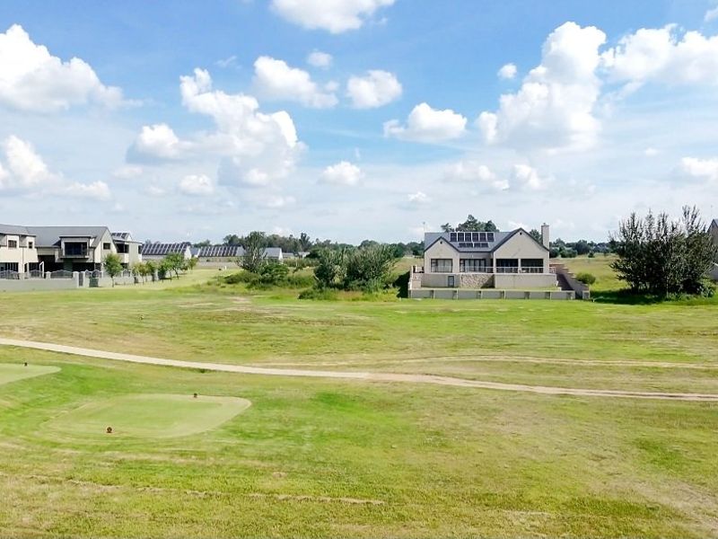 An elevated view of a residential estate featuring open green spaces, manicured lawns, and surrounding modern residential properties.