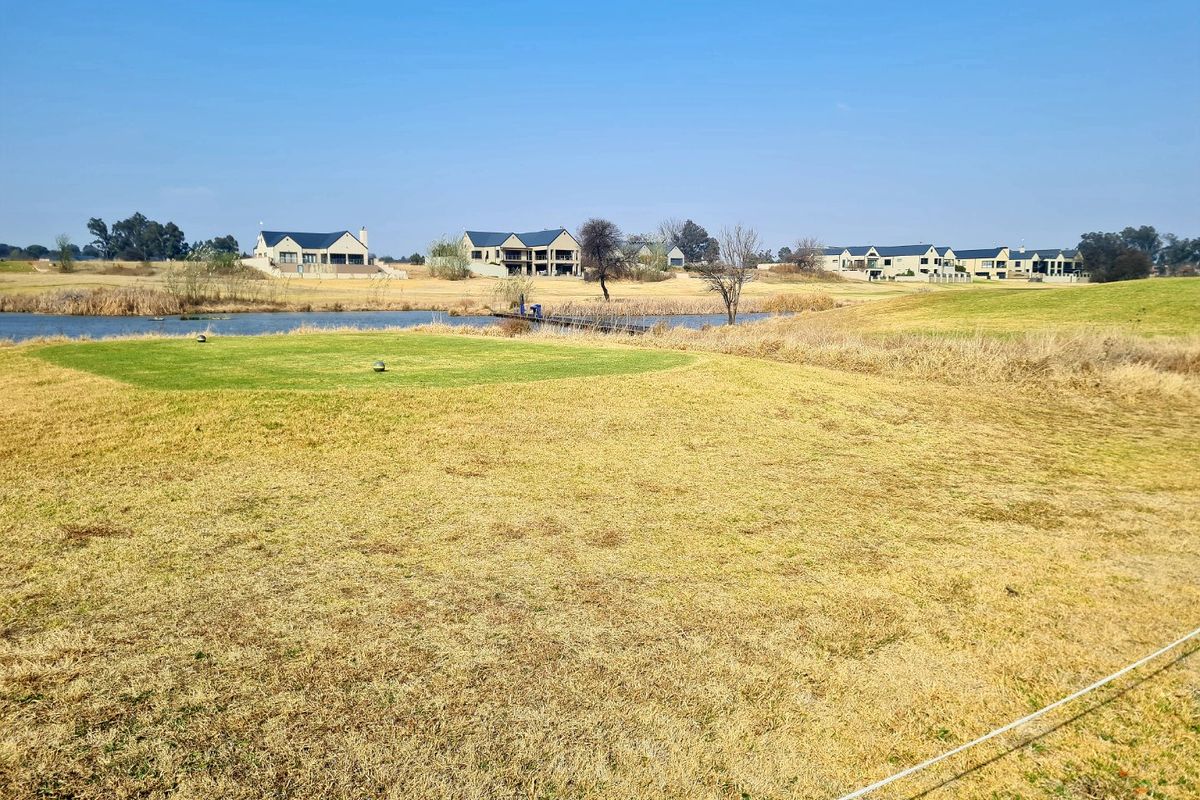 A scenic view of a residential estate featuring manicured lawns, a small lake, and surrounding multi-story homes in a peaceful setting.