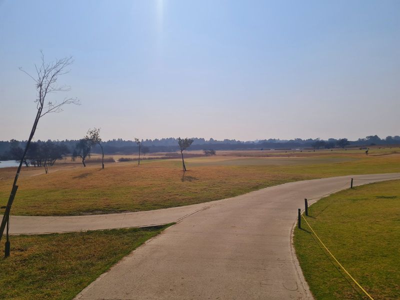 A view of the expansive vacant residential land featuring paved pathways and natural landscaping.