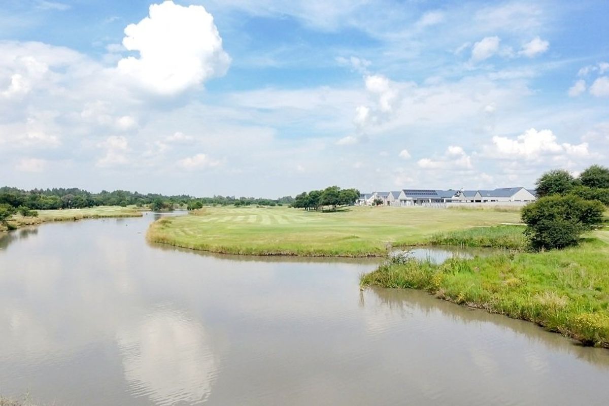 A scenic view of a tranquil lake and manicured green landscape within a residential estate setting.