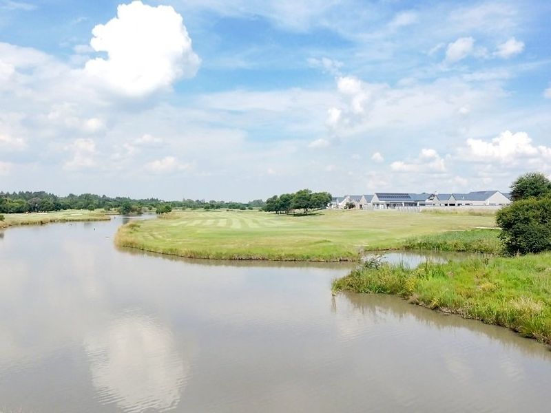 A scenic view of a tranquil lake and manicured green landscape within a residential estate setting.