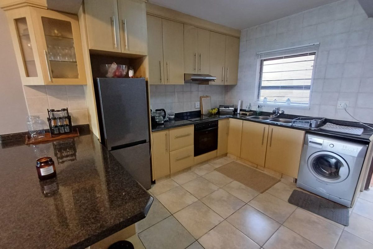 Functional kitchen featuring light wood cabinetry, granite countertops, integrated oven, extractor fan, and dedicated space for a washing machine.