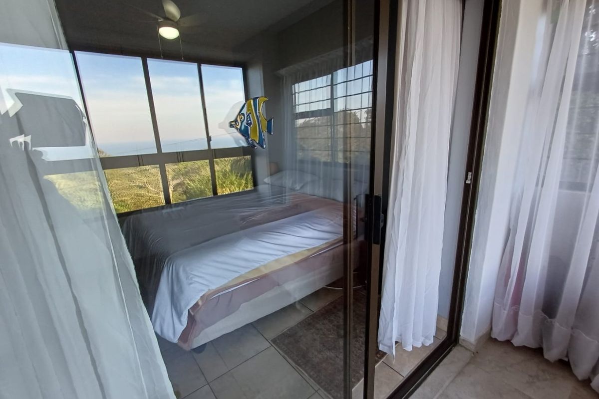 A bedroom featuring large windows with scenic views, accessible via sliding glass doors, providing natural light and a connection to the outdoors.