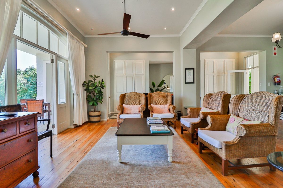 Spacious living area featuring polished timber flooring, recessed ceiling lighting, a ceiling fan, and large glass doors opening to an outdoor patio.