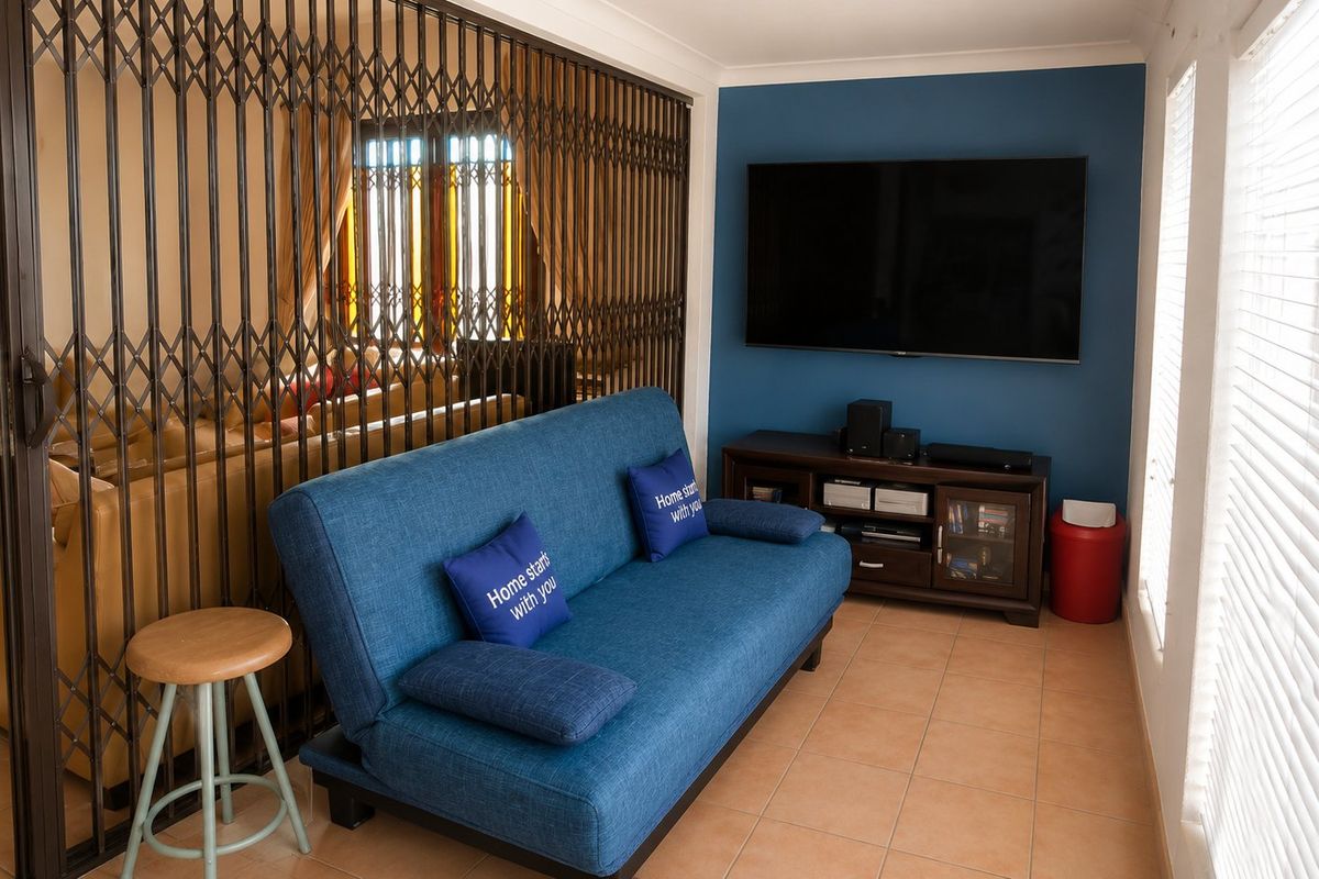 A living room featuring tiled flooring, a blue accent wall, and a retractable metal security gate separating the space from an adjacent area.
