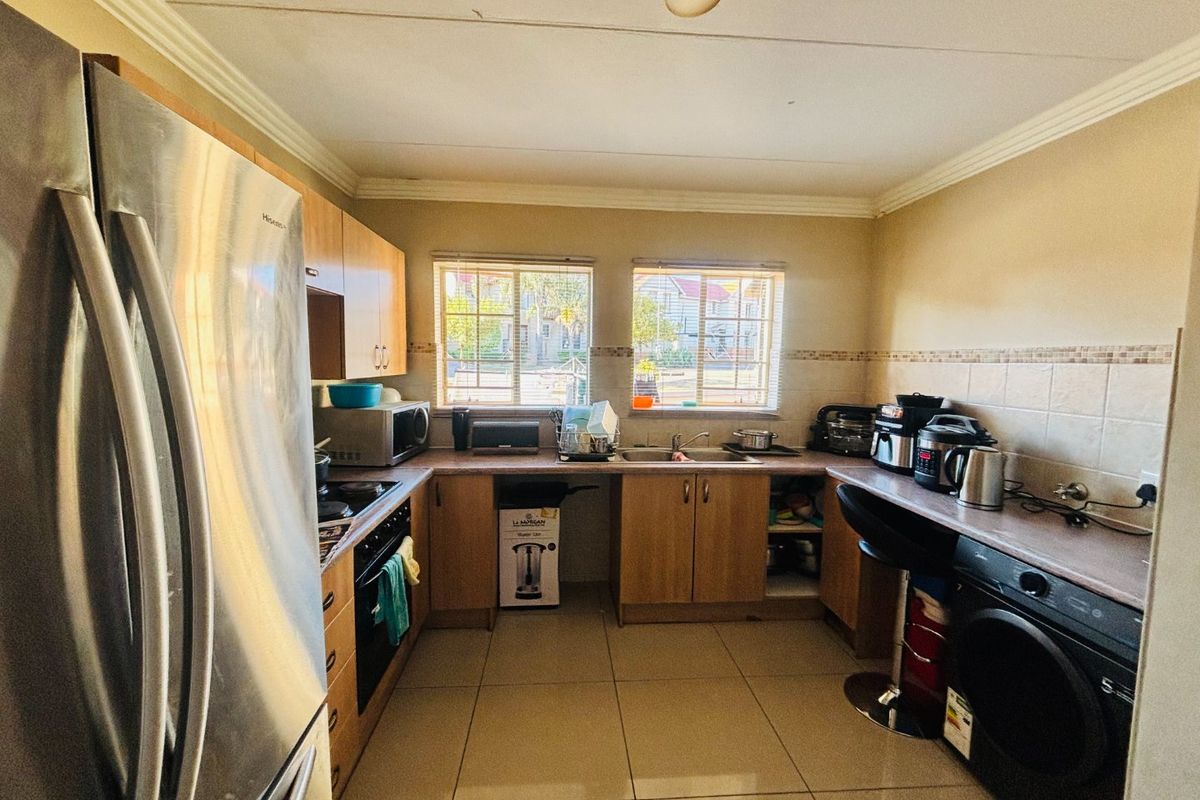 Functional kitchen featuring light wood cabinetry, tiled flooring, laminate countertops, and integrated sink with dual windows providing natural light.