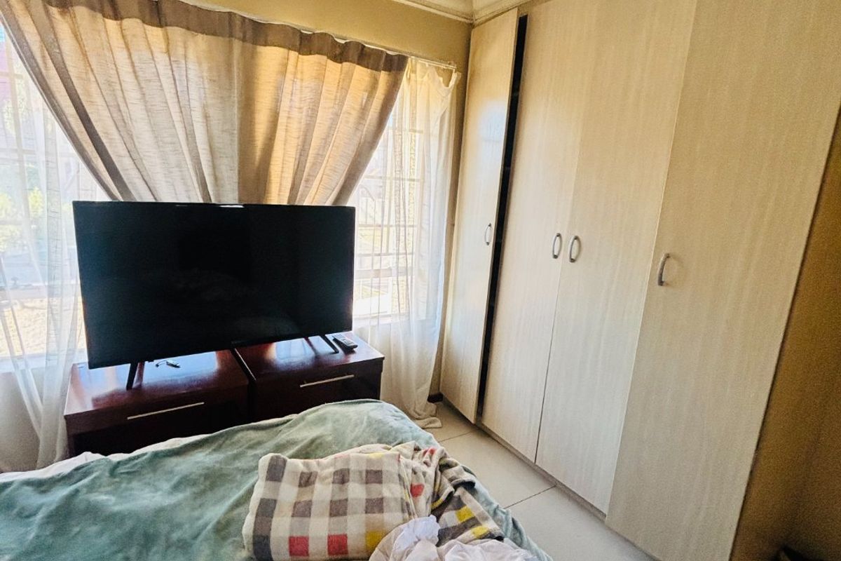 A bedroom featuring built-in wooden cupboards and tiled flooring, offering functional storage space.