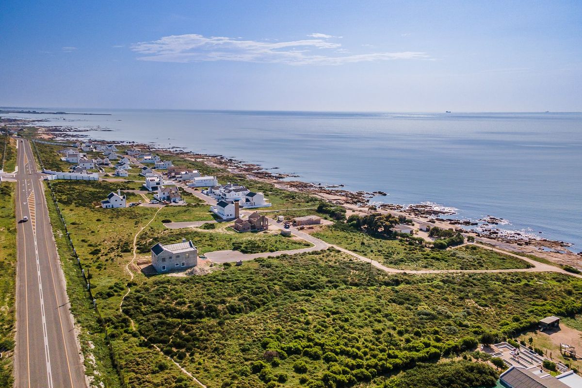 Aerial view of a coastal residential development featuring vacant land plots and established homes along the shoreline.