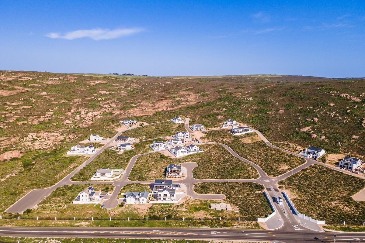 Aerial view of a residential estate development featuring paved roads and multiple modern homes situated in a natural, rocky landscape.