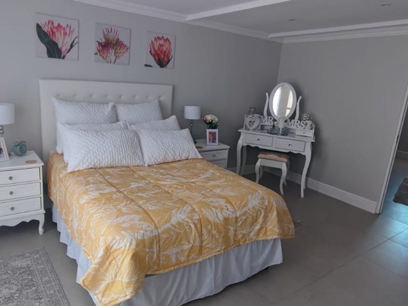 A well-maintained bedroom featuring neutral wall tones, tiled flooring, and crown molding, with an adjoining room visible through the doorway.