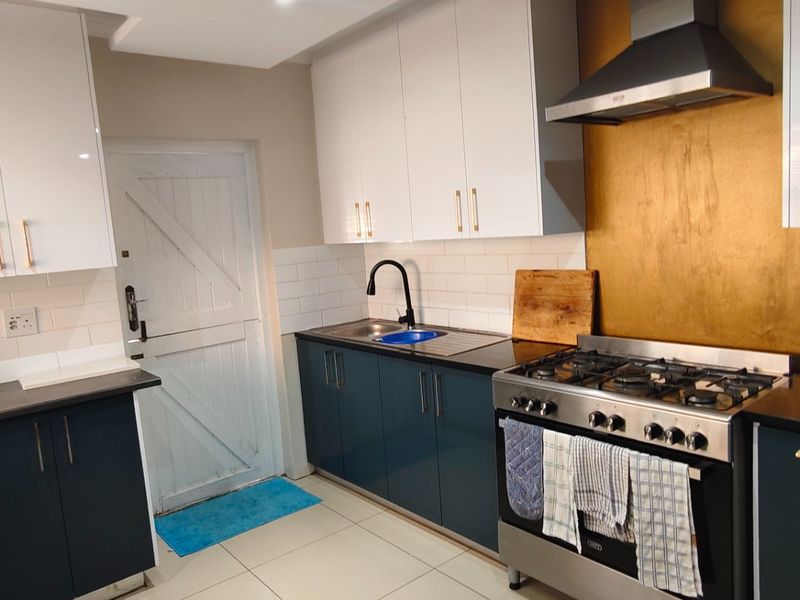 Modern kitchen featuring two-tone cabinetry, dark countertops, subway tile backsplash, and a stainless steel gas stove with a metallic splashback.