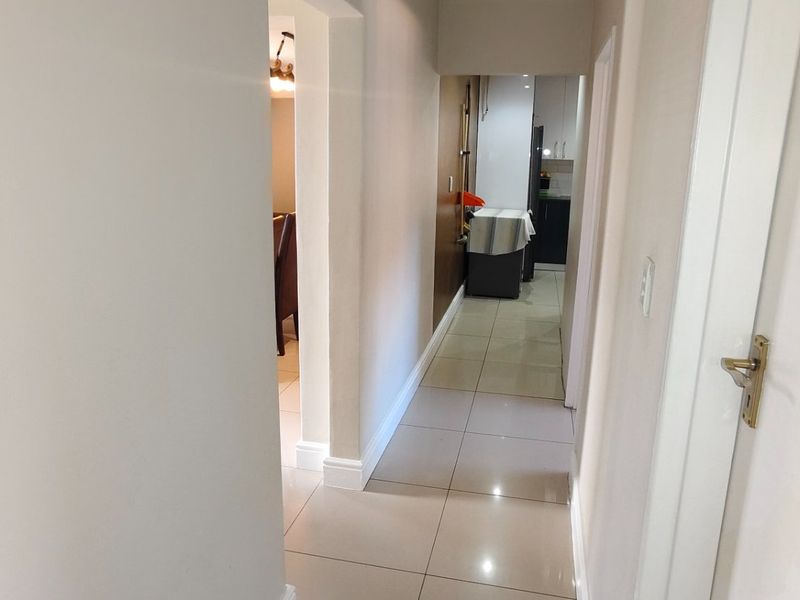 A bright interior hallway featuring neutral tiled flooring, connecting multiple living spaces within the home.