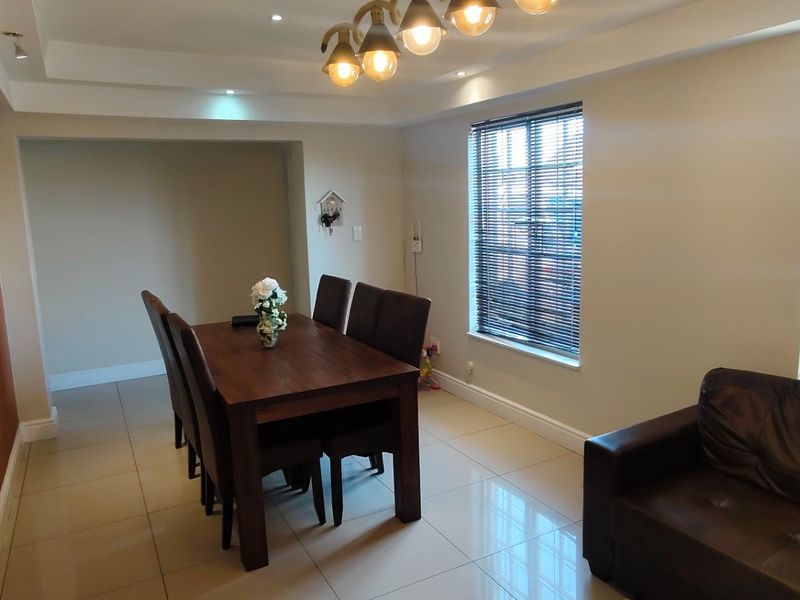 Open plan living and dining area featuring tiled flooring, recessed ceiling lighting, and large windows with fitted blinds.