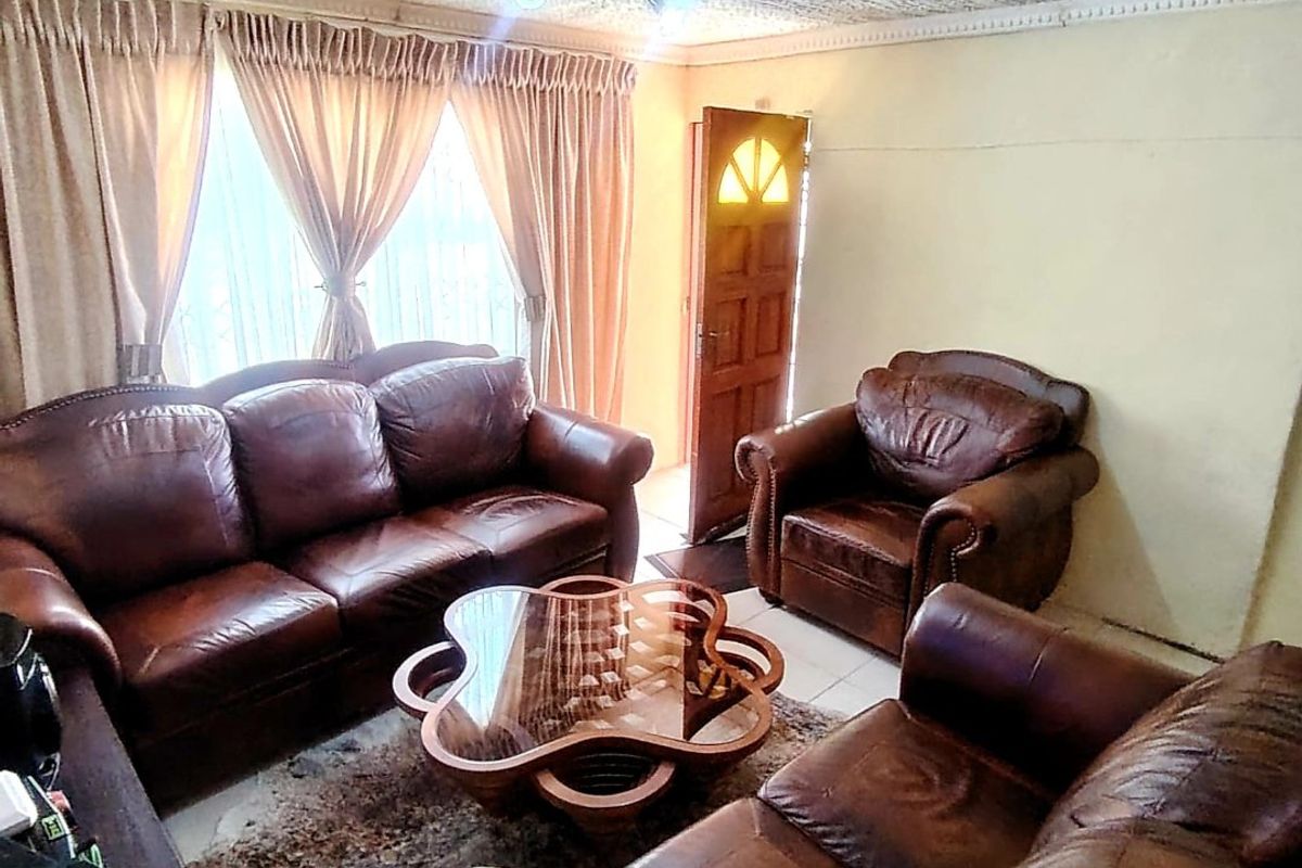 A living room featuring textured ceiling finishes, tiled flooring, and a wooden entrance door with glass inserts.