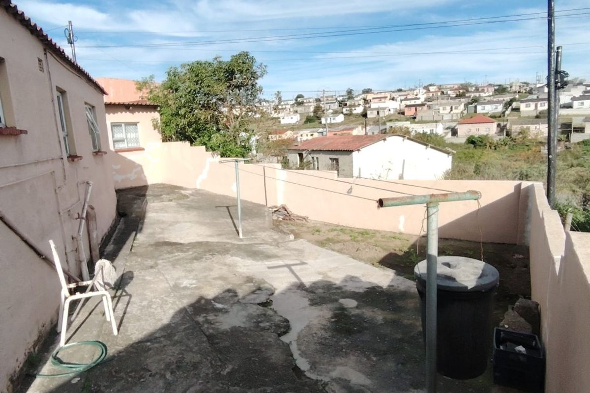 Rear exterior area featuring concrete paving, boundary walls, and a clothesline, offering a view of the surrounding neighbourhood.