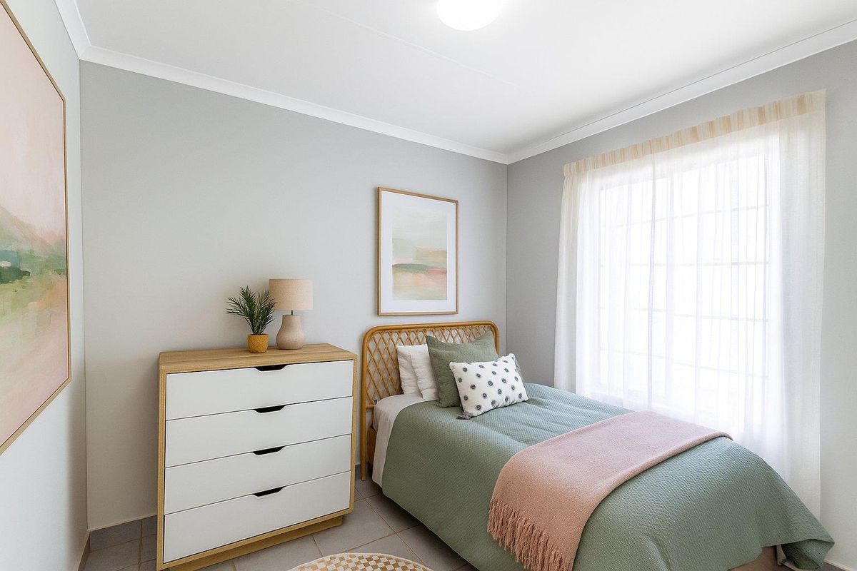 A bright and well-maintained bedroom featuring neutral wall tones, tiled flooring, and a large window with sheer curtains allowing for natural light.