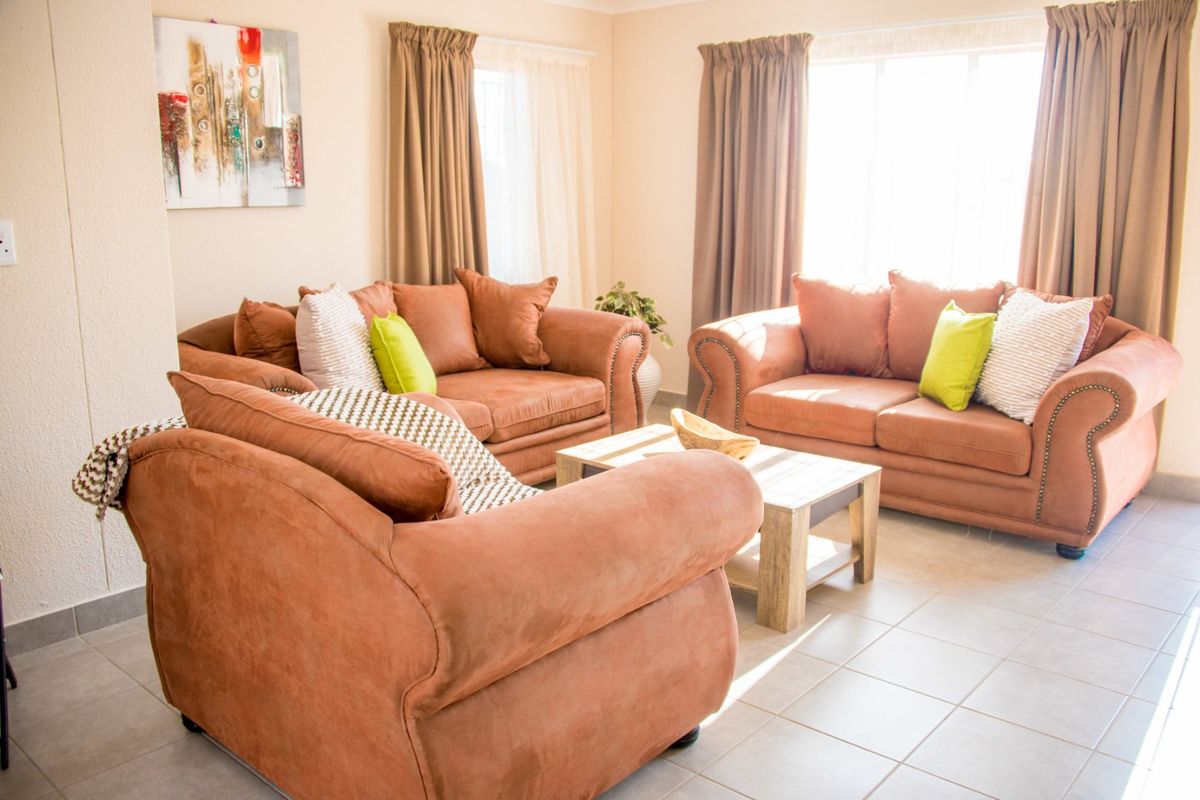A bright and spacious living room featuring neutral tiled flooring and large windows that allow for ample natural light.