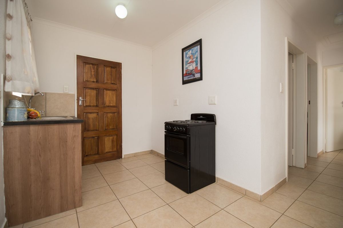 A functional kitchen area featuring tiled flooring, a built-in sink unit, and a freestanding stove.