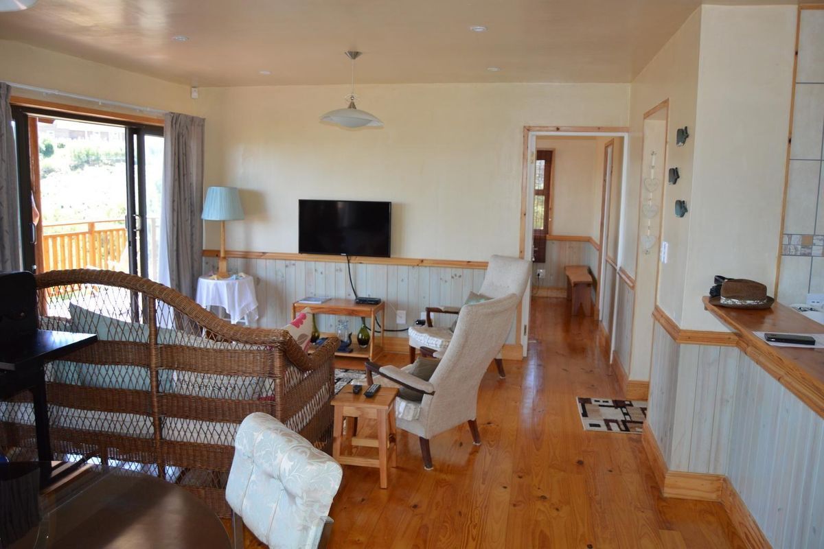 A living room featuring timber flooring and wall paneling, with a sliding glass door providing access to an outdoor balcony area.