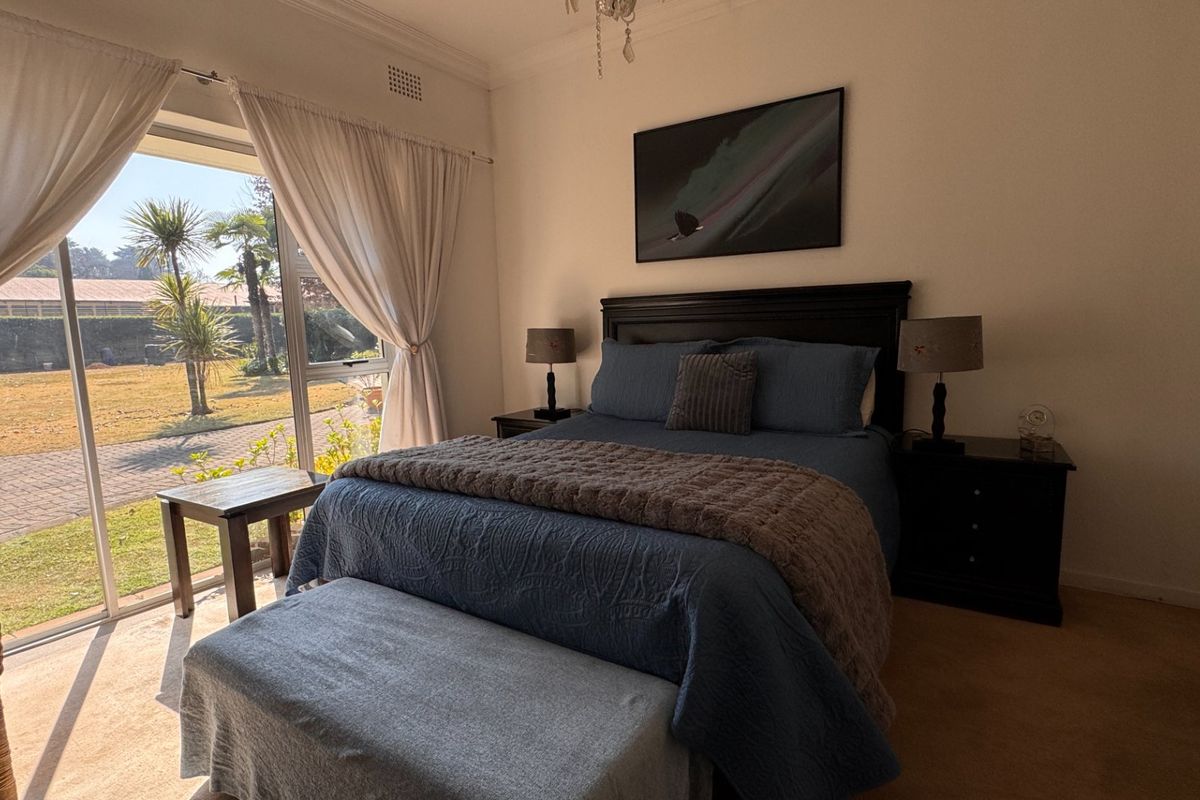 A bright bedroom featuring large sliding glass doors that provide direct access to the garden and allow for ample natural light.