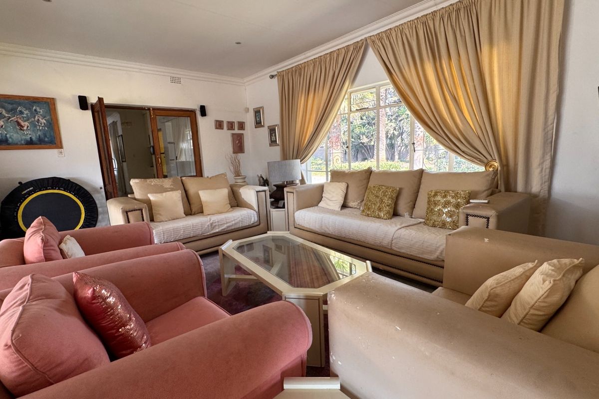 A spacious living room featuring large windows with curtains, providing natural light and access to the outdoor area.