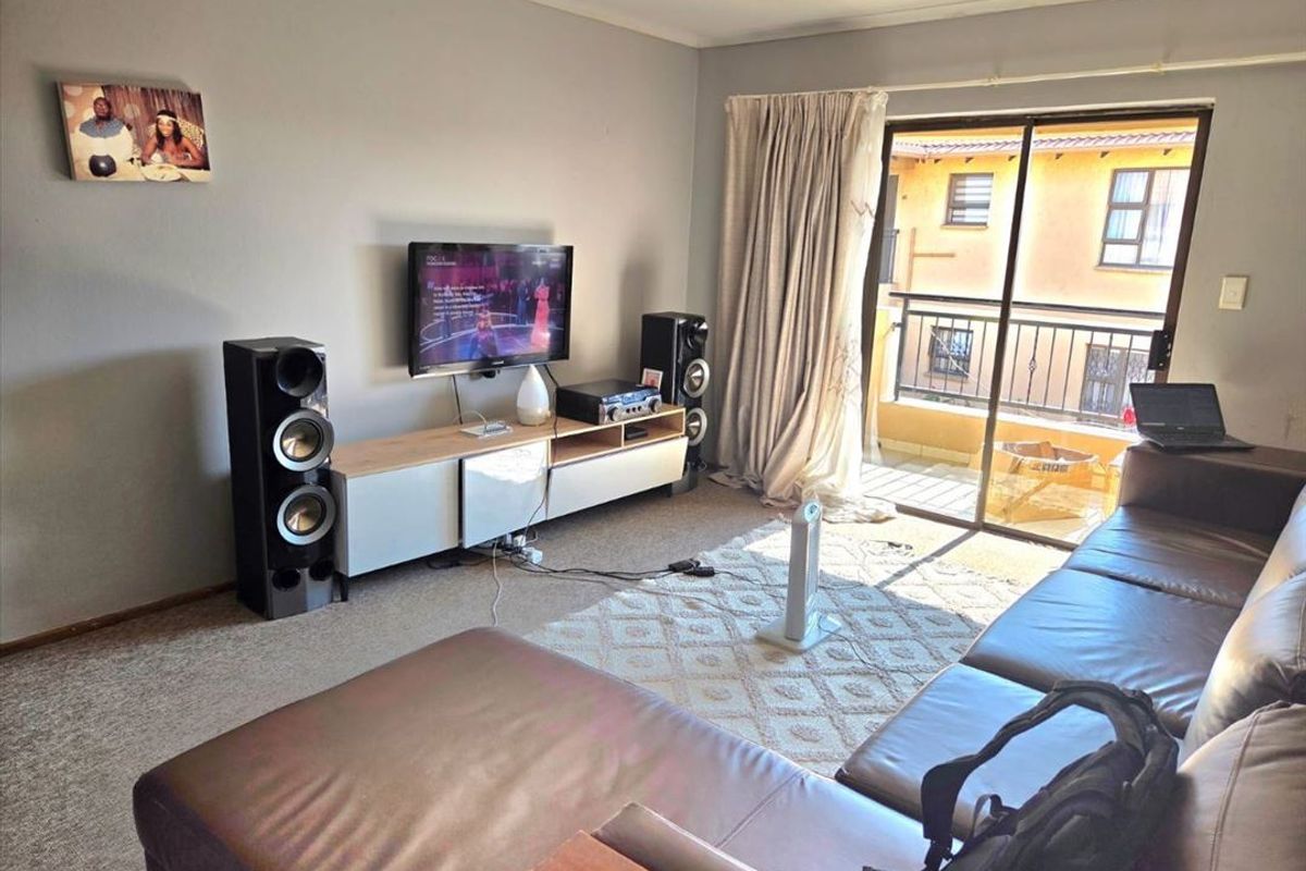 A comfortable living room featuring carpeted flooring and a sliding glass door that opens onto a private balcony.