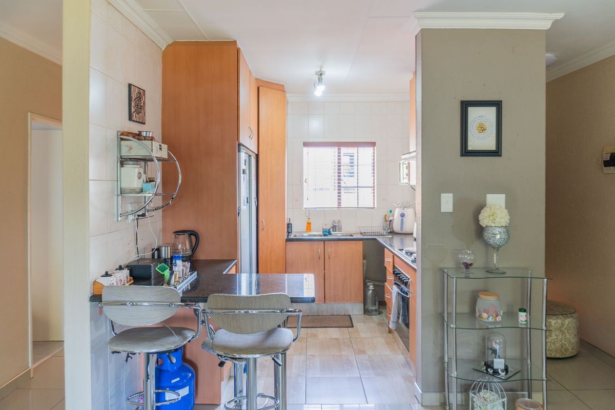 A functional kitchen featuring wooden cabinetry, a breakfast bar, tiled splashbacks, and a built-in oven, offering a practical layout for daily meal preparation.