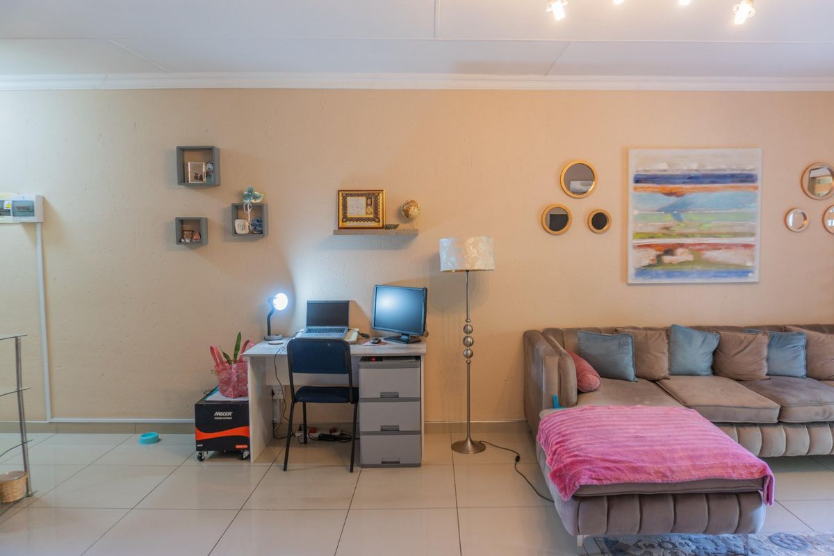 A living room area featuring tiled flooring and neutral wall finishes, providing a functional space for relaxation and home office activities.