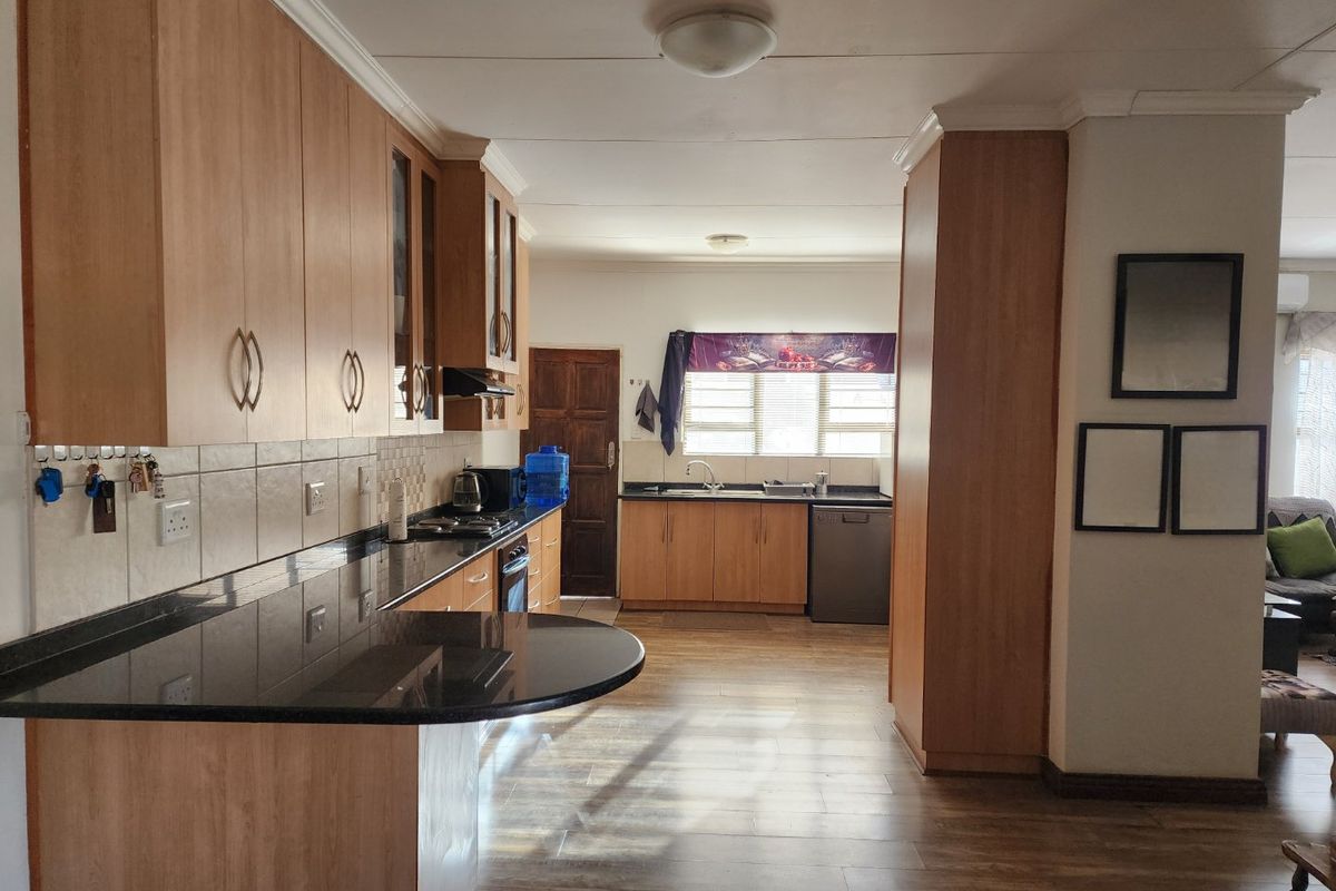 Functional kitchen featuring wood-look cabinetry, dark granite countertops, integrated oven and hob, and a double sink with tiled backsplash.