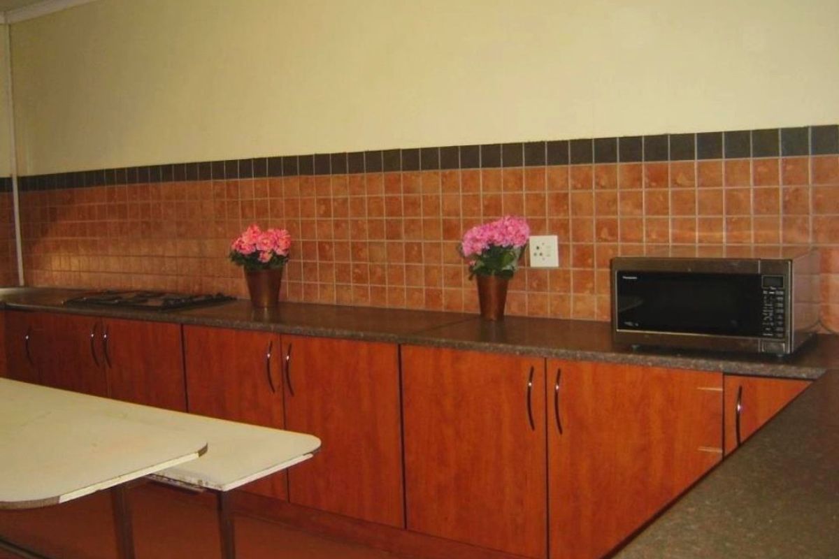 A functional kitchen featuring wood-look cabinetry, dark laminate countertops, and a tiled backsplash with a built-in cooktop.