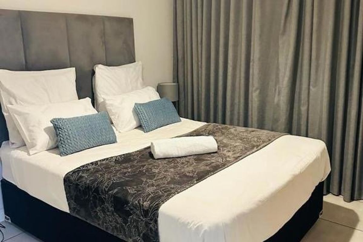 A well-maintained bedroom featuring neutral tiled flooring, a neutral color palette, and floor-to-ceiling curtains.