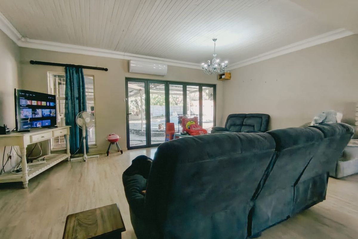 Spacious living room featuring light wood-look flooring, a white tongue-and-groove ceiling, and large sliding glass doors providing direct access to the outdoor area.