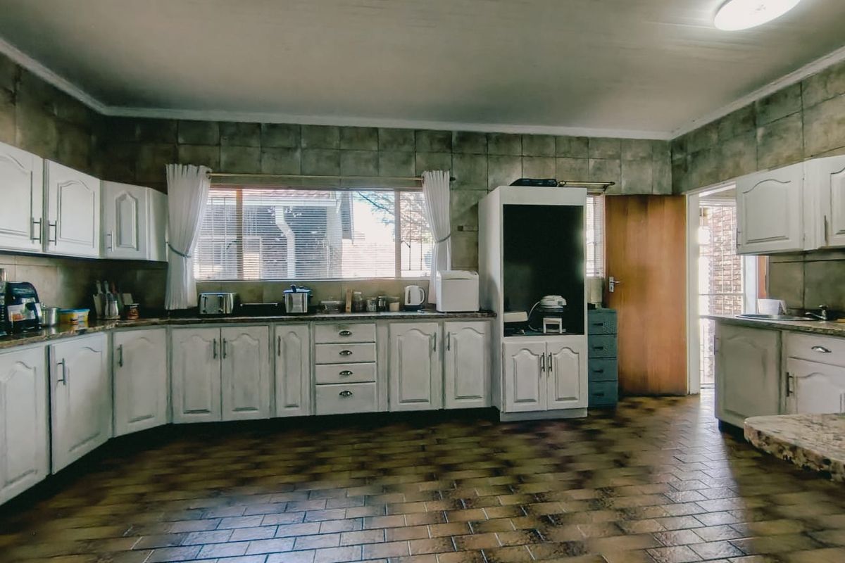 Spacious kitchen featuring white cabinetry, granite-look countertops, and tiled flooring, offering a functional layout with ample storage and workspace.
