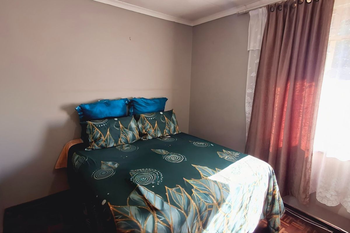 A standard bedroom featuring parquet flooring and natural light through a window with installed curtain rails.