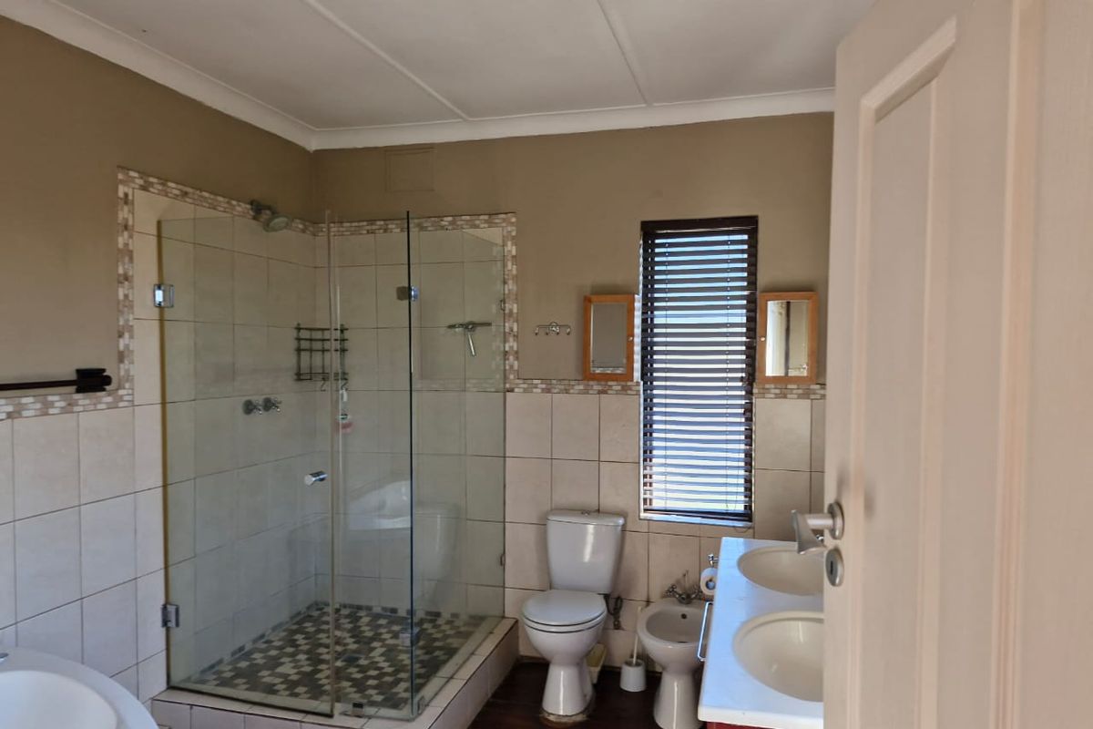 A functional bathroom featuring a glass-enclosed shower, dual vanity basins, a toilet, and a bidet with tiled wall finishes.