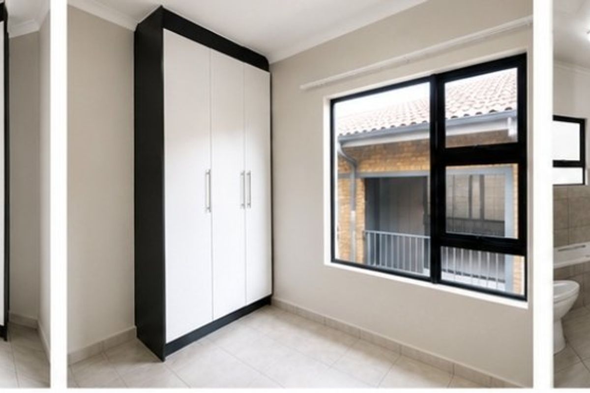 A bright bedroom featuring built-in cupboards, tiled flooring, and an en-suite bathroom with a bathtub.