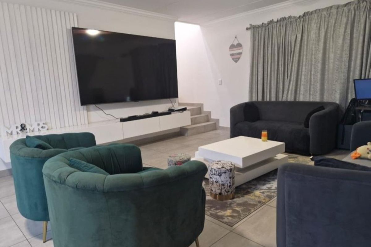 A modern living room featuring large format floor tiles, a built-in floating media console, and a decorative vertical slat feature wall.
