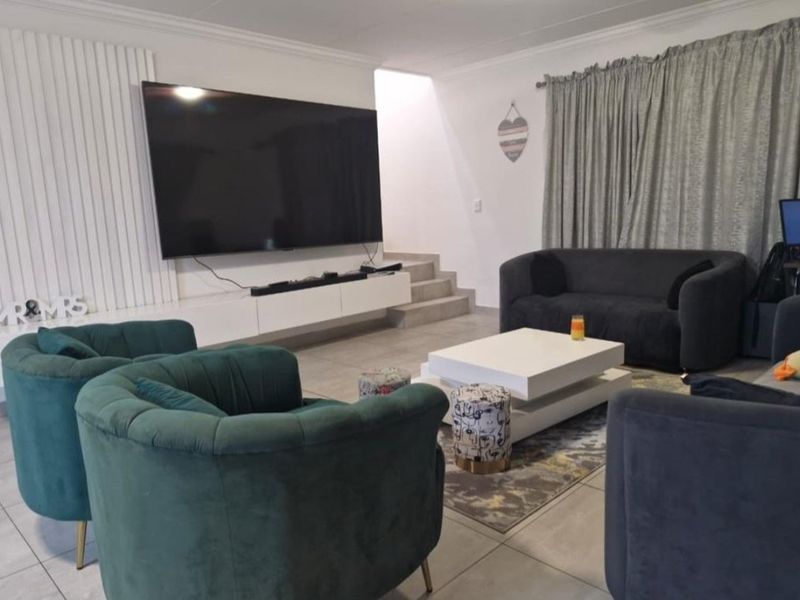 A modern living room featuring large format floor tiles, a built-in floating media console, and a decorative vertical slat feature wall.