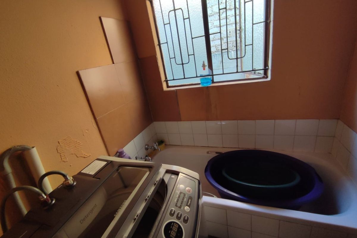 A functional bathroom featuring a bathtub with tiled surround and a dedicated space for laundry appliances.