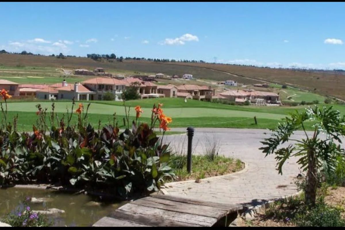 A scenic view overlooking a residential golf estate with manicured greens, landscaped gardens, and surrounding rolling hills.