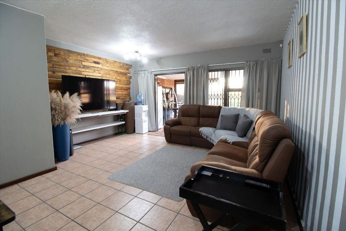 Spacious living room featuring tiled flooring, a decorative timber-clad feature wall, and direct access to an adjoining patio area.