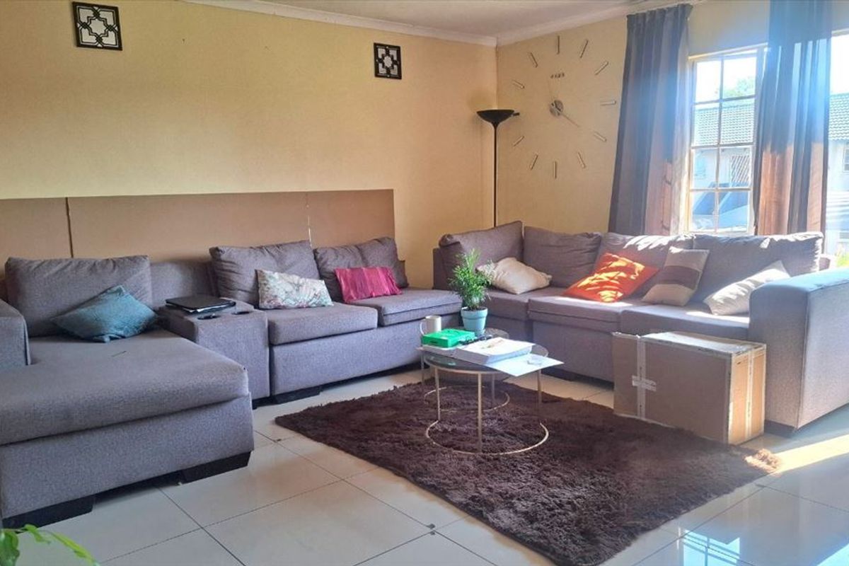 A living room featuring tiled flooring and large windows that provide natural light, creating a functional and comfortable living space.