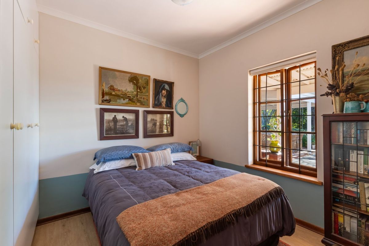 A cozy bedroom featuring built-in wardrobes, timber-framed windows, and light-toned flooring, offering a comfortable and functional living space.