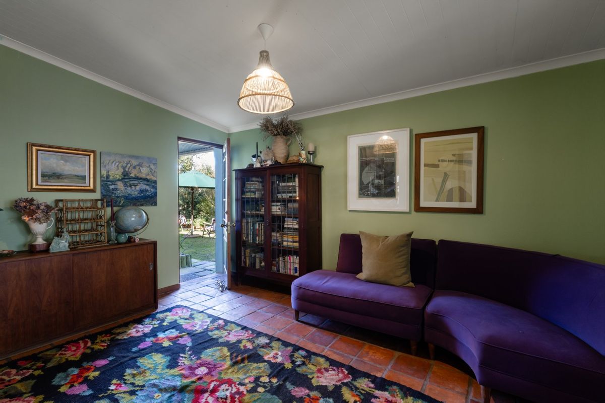 A cozy living room featuring terracotta tile flooring and direct access to the rear garden through a single door.