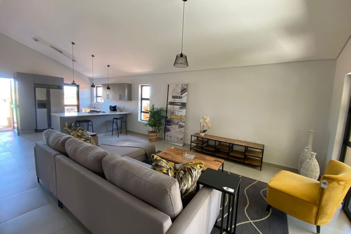 Open-plan living area featuring a modern kitchen with a breakfast island, sleek cabinetry, and tiled flooring throughout.