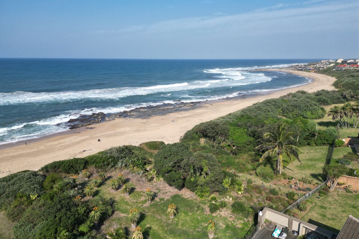Aerial view showcasing the property's proximity to the coastline, featuring landscaped garden areas and a private pool deck.