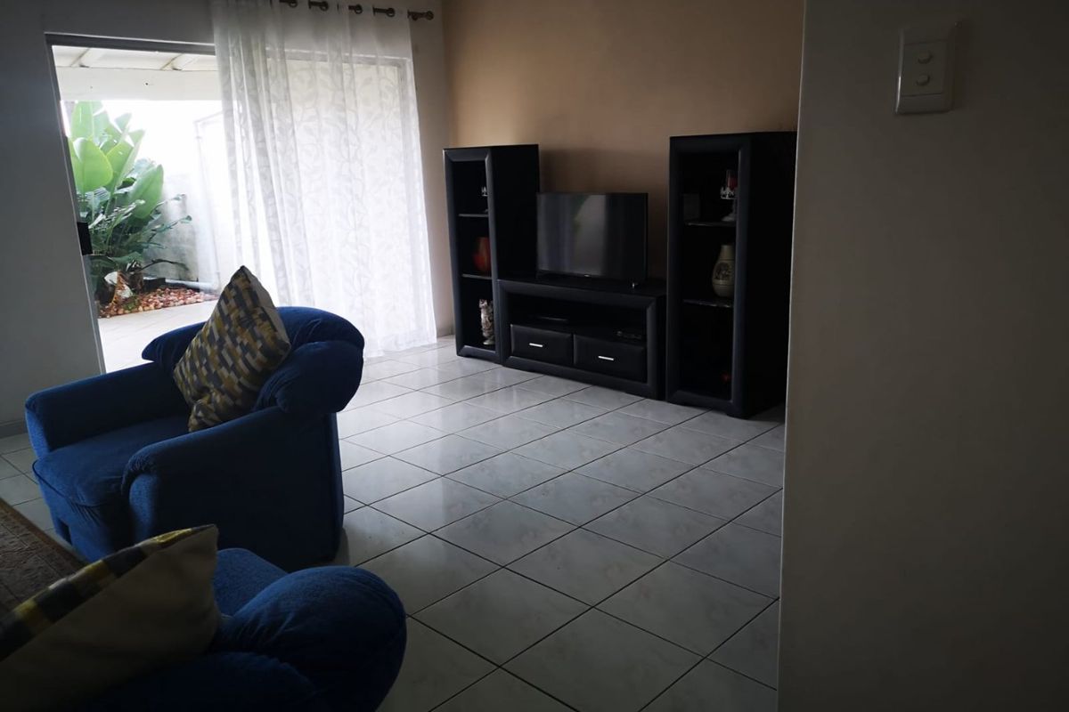 A living room featuring tiled flooring and a sliding glass door providing access to an outdoor patio area.