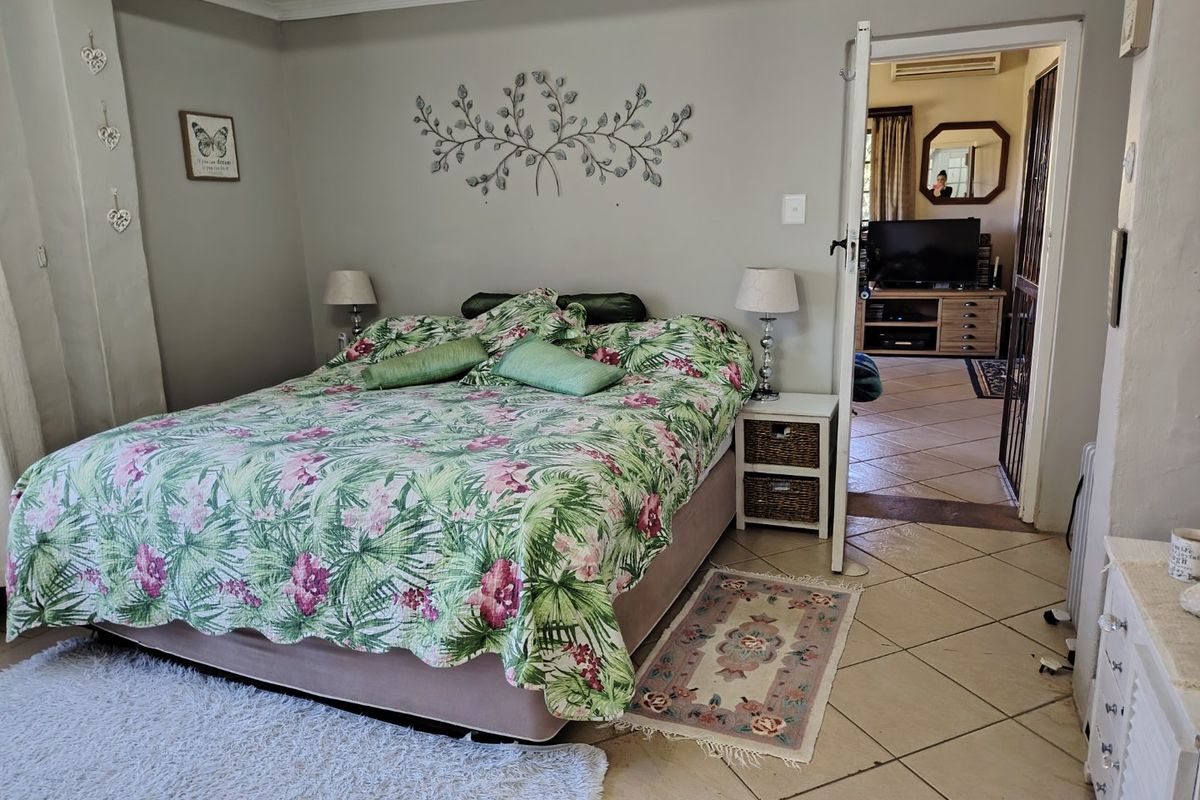 A bedroom featuring tiled flooring and a doorway leading to an adjacent living area with an air conditioning unit.