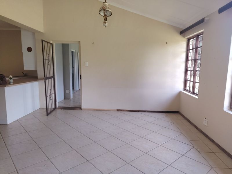 Open plan living area featuring tiled flooring, vaulted ceilings, and a breakfast counter connecting to the kitchen space.